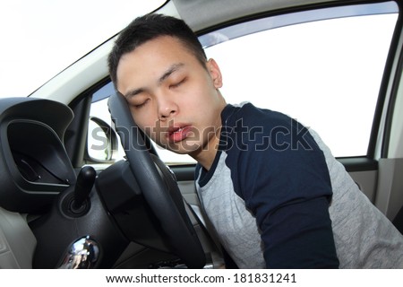 A young man falling asleep at the steering wheel