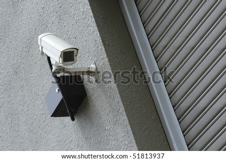 A security camera mounted on a wall outside a shop