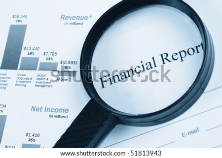 A magnifying glass on some papers with the words Financial Report magnified