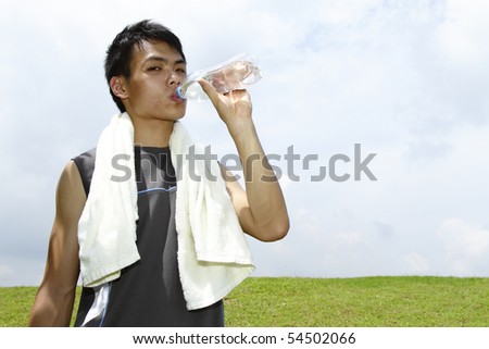 A young Asian man drinking after a work-out