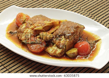 A dish of spicy and sour wolf-herring fish served with herbs, tomato, lemon and carrots.