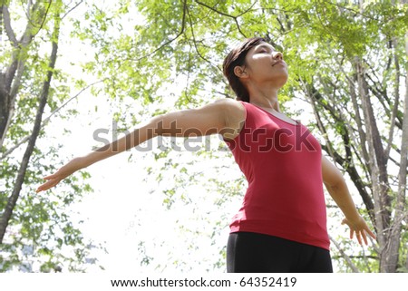 An Asian woman spreading her arms at a park