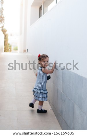The beautiful caucasian  baby girl walking alone in street