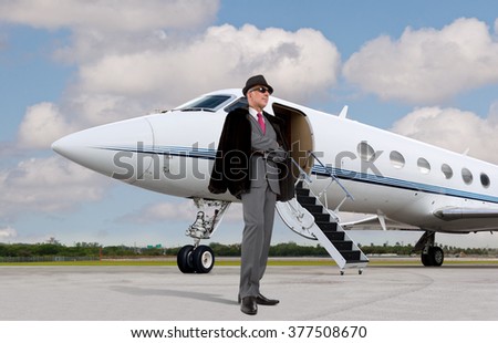 Handsome business man on the steps of a private jet wearing a hat