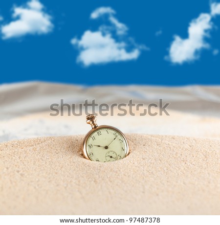 Vintage pocket watch semi buried in the sand