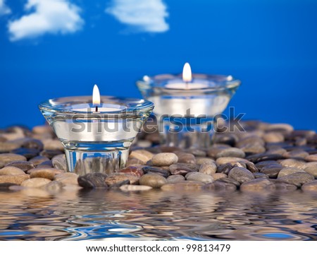 Votive candles placed on rocks in the water