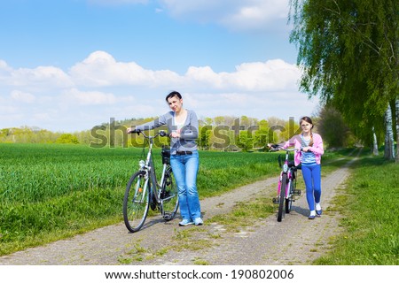 Bike riding - young girl with mother on bike, active family concept