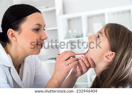 Doctor check throat of little girl.