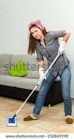 Brunette woman mopping the floor while smiling