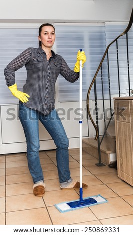 Brunette woman mopping the floor while smiling