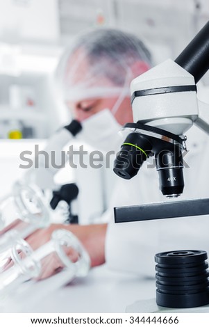 scientist working in the lab, in protective mask , examines a with liquid