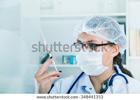 healthcare and medicine concept - female doctor in mask holding syringe with injection.toned image