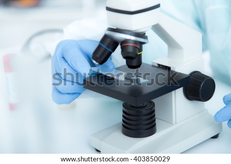 woman in a laboratory microscope with microscope slide in hand.toned image.