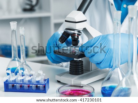 woman in a laboratory microscope with microscope slide in hand.toned image.