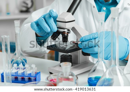 men in a laboratory microscope with microscope slide in hand.toned image.