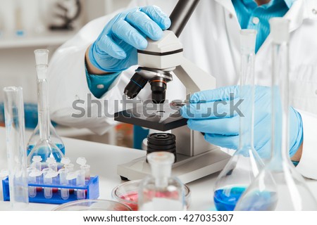 men in a laboratory microscope with microscope slide in hand