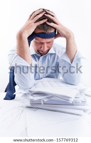 Too much work. Portrait of desperate businessman sitting at office desk full with papers.