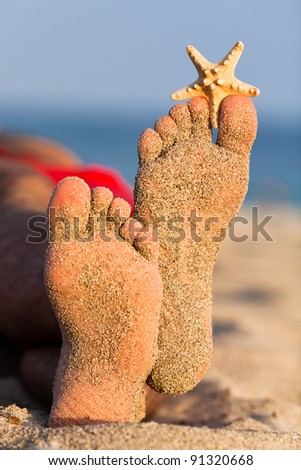 Man relaxing on the beach with sandy feet and starfish.