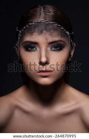 Fashion portrait of young woman with dark dusty make up and head accessory of chains