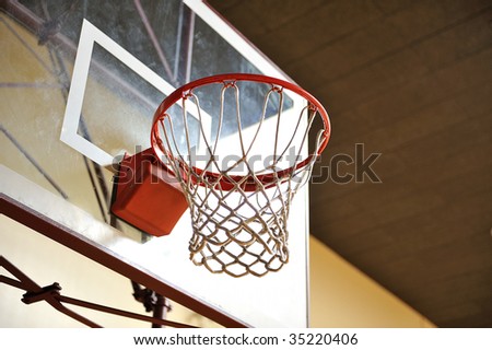 A basketball hoop with a glass backboard in an empty gym
