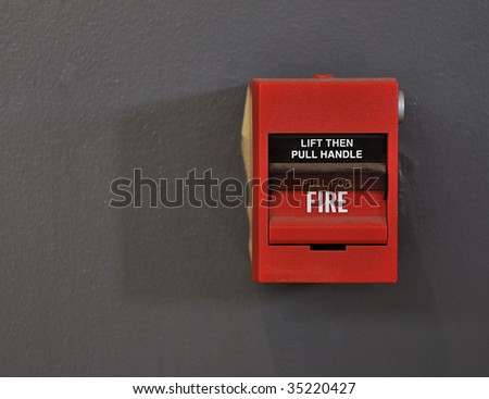 Close-up shot of a red fire alarm against a grey painted wall