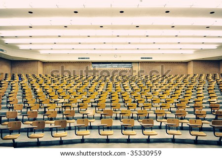 A large amount of empty seats with tables in a lecture hall