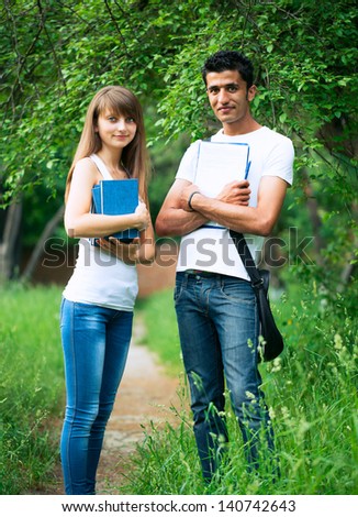 Two students guy and girl studying in park with book outdoors