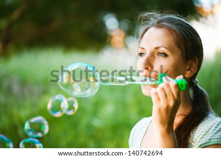 Close-up portrait of a girl blowing soap bubbles in the park