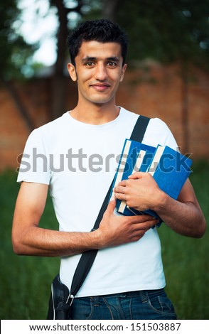 Arab male student with books outdoors looking very happy