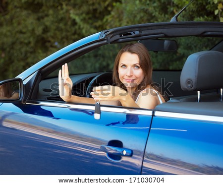 Smiling caucasian woman showing key in a cabriolet car