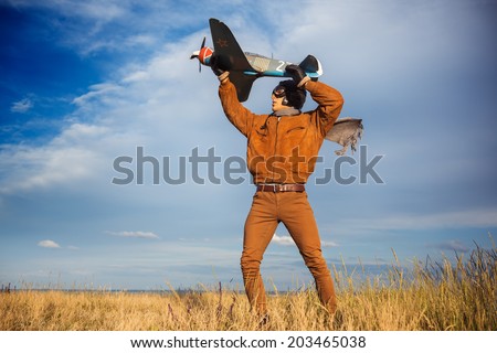 Young guy in vintage clothes pilot with an airplane model outdoors