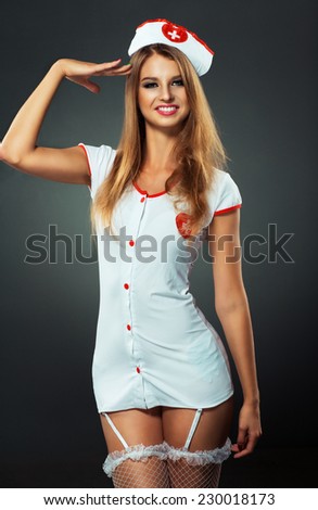 Young and beautiful dancer in nurse costume posing on studio background