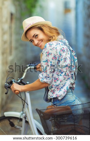 Beautiful happy woman with bicycle on street of old town
