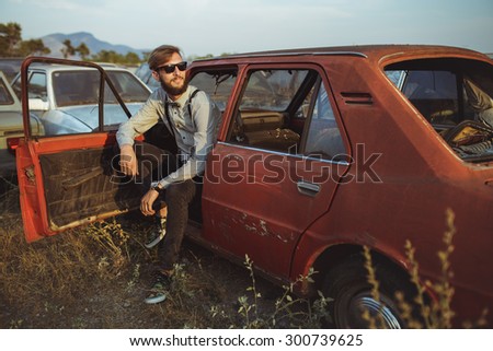 Portrait of a young handsome stylish man, wearing shirt and bow-tie with old cars
