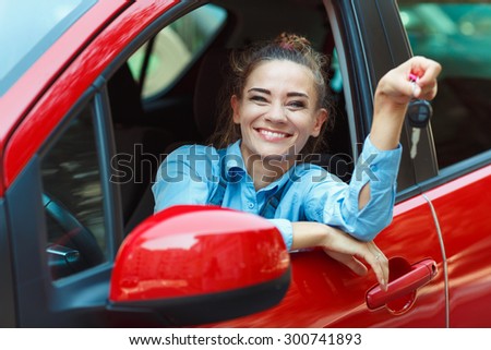 Young cheerful woman sitting in a car with keys in hand - concept Rent a car