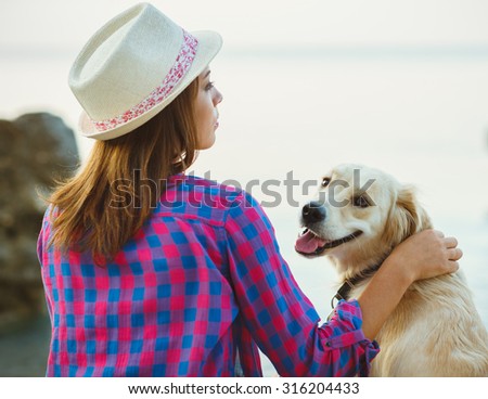 Summer vacation - woman with a dog on a walk on the beach