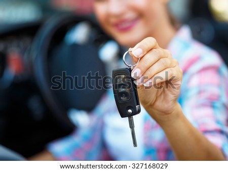 Young woman standing near a convertible with keys in hand - concept of buying a used car or a rental car