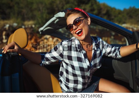 Beautiful pin up woman sitting in cabriolet, enjoying trip on luxury modern car with open roof, fashionable lifestyle concept
