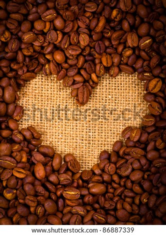 Heart shape created with coffee beans on a sacking background