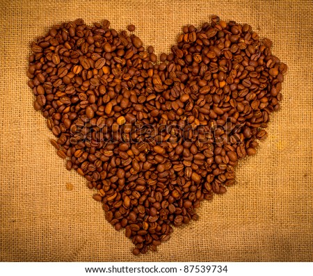 Heart shape created with coffee beans on a sacking background
