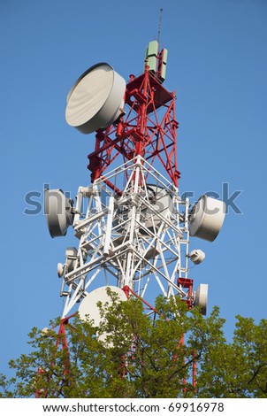 Huge communication antenna tower behind tree