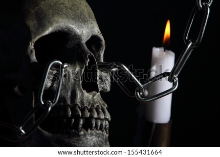 A skull chained through the eye sockets with candle.