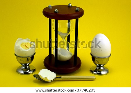 Two boiled eggs in cups with an egg timer