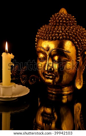a golden Buddha reflected lit by candle light
