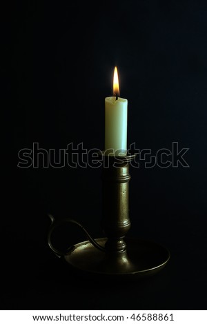 a lit candle in a brass candle holder