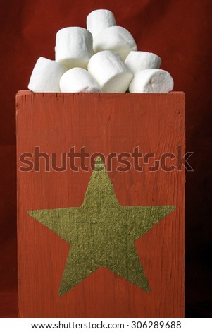 red wood box with gold star filled with white marshmallows on red background