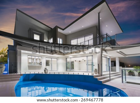 Modern new luxurious mansion exterior with swimming pool and reflections at dusk with pink and blue sky on the Gold Coast, Queensland, Australia
