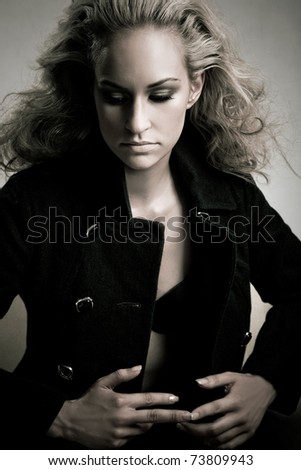 Professional model posing on white background in black coat with styled hair by hairdresser. Half length shot.