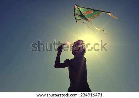 Boy flying a kite on beach at sunrise