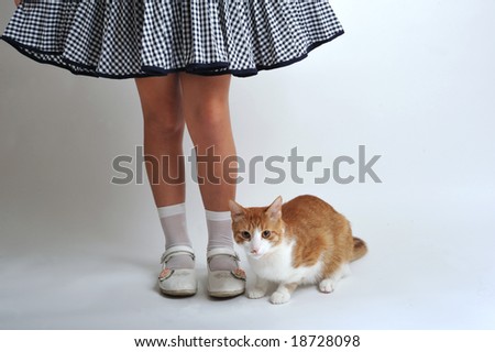 A girls legs and his cat standing side by side
